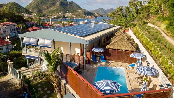 A resort with a swimming pool, sun loungers, and a view of the sea.