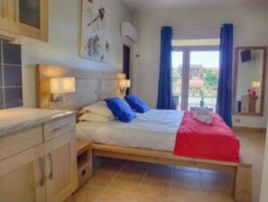 Cozy retreat with a comfortable bed, wooden cabinet, and small table.