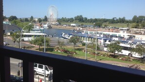Blick auf einen Uferbereich mit Riesenrad, Booten und einem Bus.