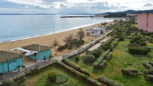 Un hotel frente al mar con vista a la playa, un edificio con techo de paja y setos cuidadosamente recortados.