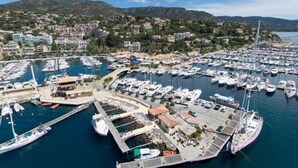 Un puerto deportivo con numerosas embarcaciones amarradas, rodeado de edificios residenciales y colinas al fondo.