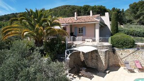 A Mediterranean-style villa with a stone entrance, a balcony with white railings, and a pool area with lounge chairs. - Vacation rental house with pool MERINDOL LS2-153 (Mérindol)