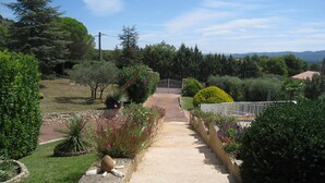 A garden pathway leading to a gated entrance surrounded by various plants and trees. - Vacation rental house with pool MERINDOL LS2-153 (Mérindol)