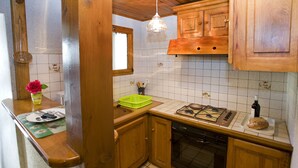 A kitchen with wooden cabinets, a gas stove, a dishwasher, and a window with a basket on the counter. - Beautiful vaulted house dating from 1647 (Jeanne's house) (La Malène)