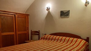 A bedroom with a bed, wooden wardrobe, and a painting on the wall. - Beautiful vaulted house dating from 1647 (Jeanne's house) (La Malène)