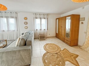 Un salon avec un canapé, une armoire en bois et un tapis à motifs.