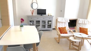 A modern living room with a dining table, two chairs, a sofa with cushions, a TV, and a cabinet with glass doors. - APARTAMENTOS AQUARIUM (REF 31). NEXT TO THE BEACH. RENOVATED. (Roses)