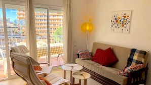 A modern living room with a sofa, two armchairs, a small table, and a balcony with a table and chairs. - APARTAMENTOS AQUARIUM (REF 31). NEXT TO THE BEACH. RENOVATED. (Roses)