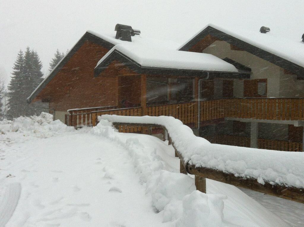 A wooden cabin with a snow-covered roof and a wooden deck.