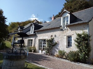 A stone building with a sloped roof, multiple windows, and a gravel driveway.