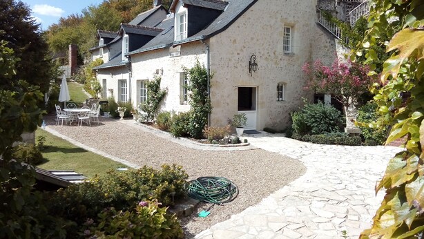 Una casa de pedra tradicional amb un camí de grava, un jardí petit i mobiliari exterior.