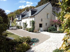 Une maison traditionnelle en pierre, avec une allée en gravier, un petit jardin et du mobilier d’extérieur.