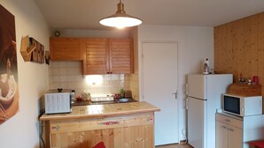 Une cuisine compacte avec des meubles en bois, un réfrigérateur blanc, un four à micro-ondes et un petit évier.