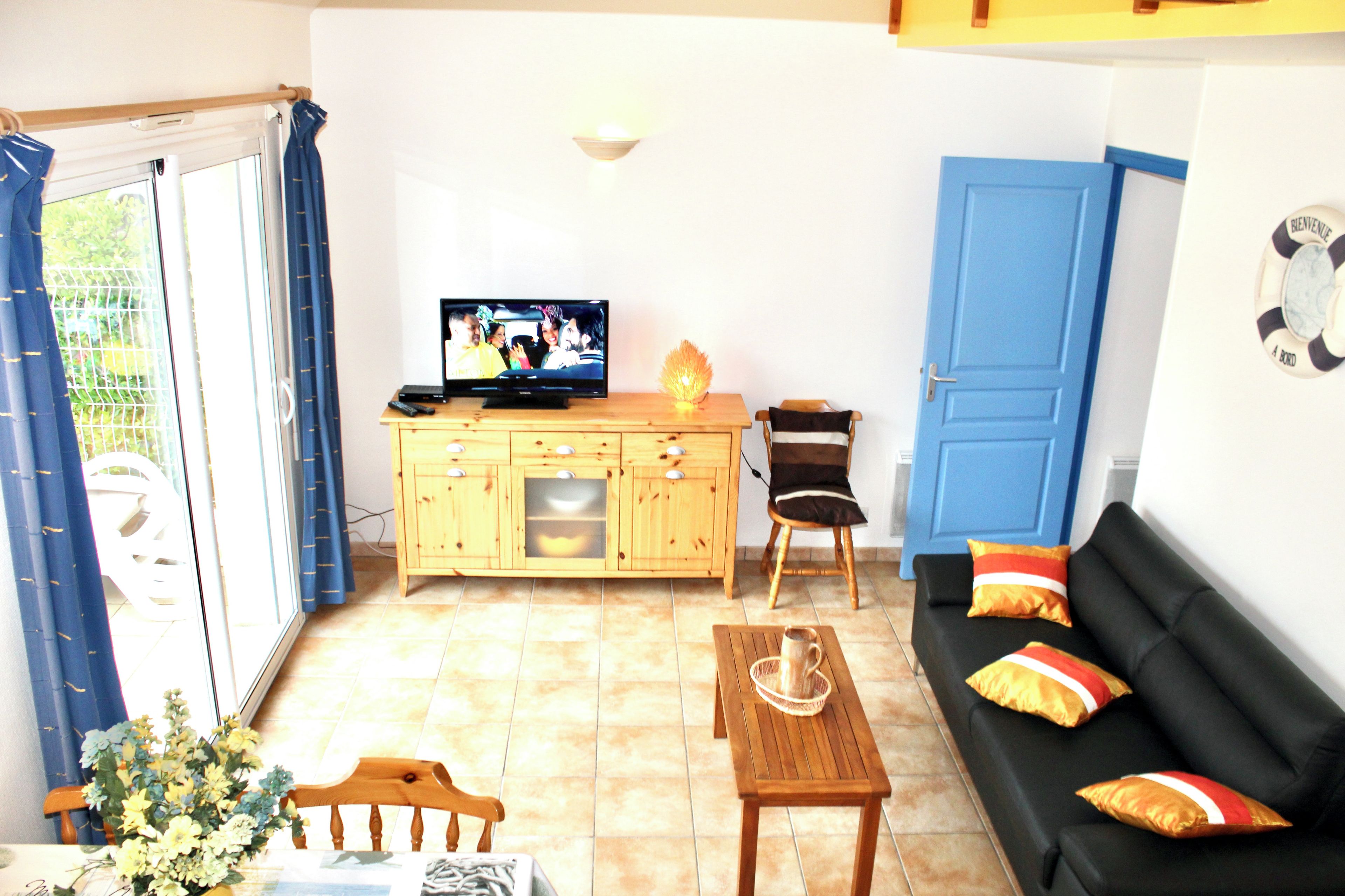 A living room with a sofa, a wooden table, a television, and a cabinet.
