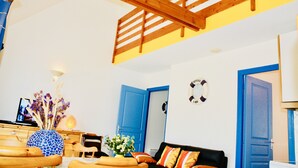 A living room with a wooden ceiling, blue doors, a sofa, and a vase with flowers. - 40 meters from the BEACH / SEA Quiet house, Private Parking, Charges INCLUDED (Barneville-Carteret)