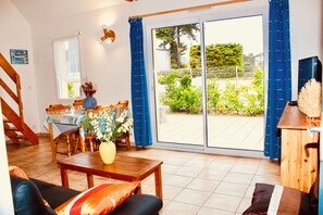 Un vaste espace de vie comprenant une table à manger, un canapé et une vue sur le jardin grâce à de grandes portes-fenêtres coulissantes.