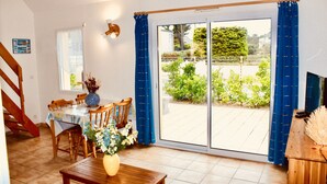 A dining area with a table set for four, a wooden bench, and a vase with flowers. - 40 meters from the BEACH / SEA Quiet house, Private Parking, Charges INCLUDED (Barneville-Carteret)