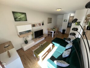 A modern living room with a TV, sofa, and dining area.