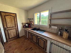 A kitchen with a wooden door, a window, a sink, and cabinets.