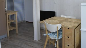 Une pièce comprenant une table à manger en bois, des chaises blanches, une petite table d’appoint en bois et un miroir fixé au mur.