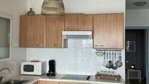 Una cocina moderna con armarios de madera, un microondas, una estufa y un colgador para ollas.