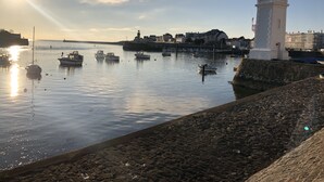 Ein Hafen mit Booten, einem Leuchtturm und Gebäuden im Hintergrund.