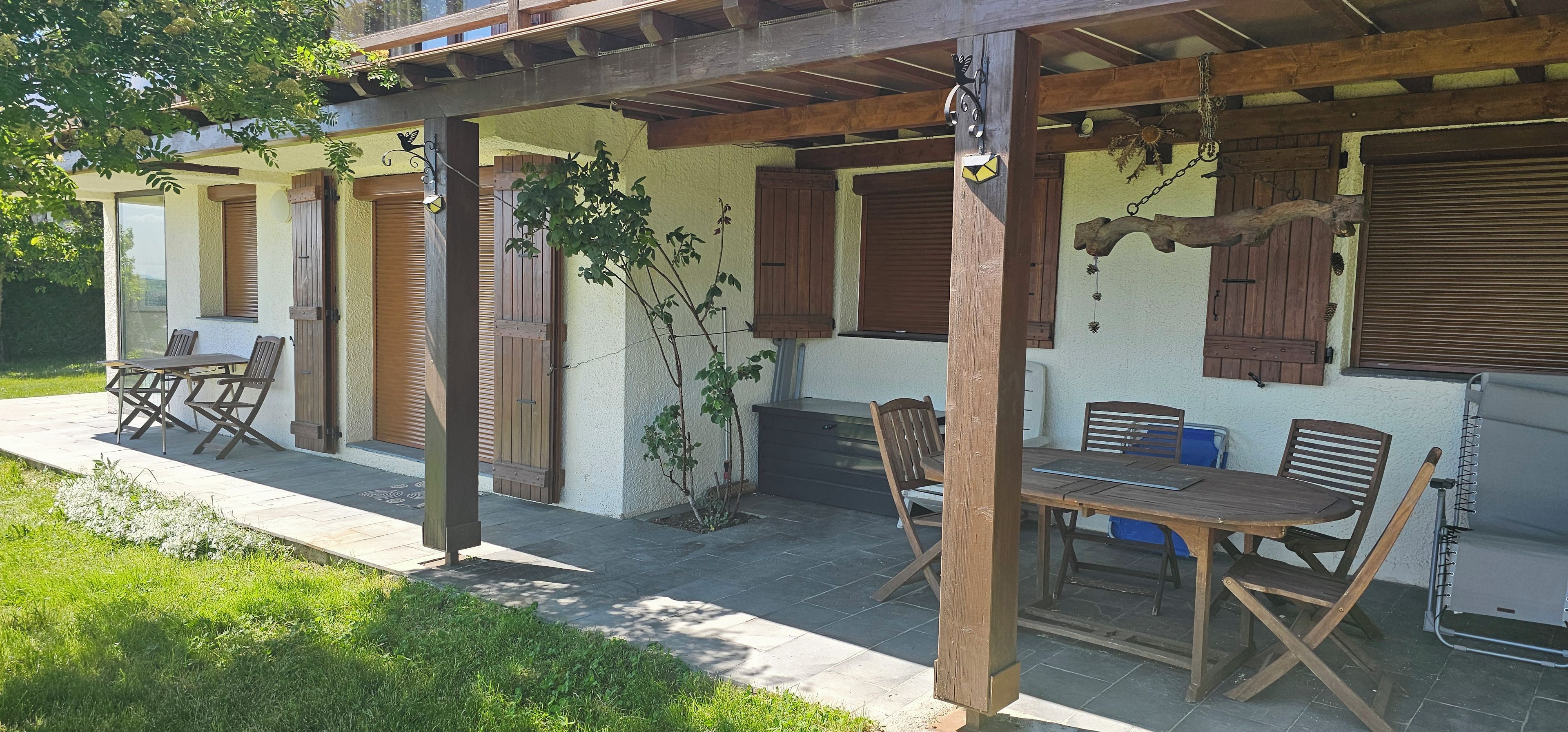 Un patio exterior con mobiliario de madera y una zona cubierta.