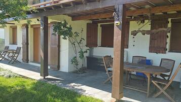 Un patio exterior con mobiliario de madera y una zona cubierta.