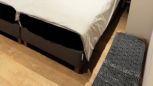 Une chambre avec un lit, une planche de surf accrochée au mur et un petit tapis.
