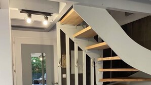 A modern interior with a spiral staircase, a door leading to an outdoor area, and a compact kitchen area.