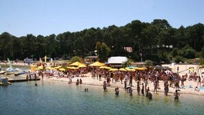 A crowded beach with yellow umbrellas and people swimming.