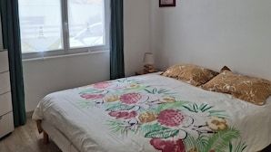 Une chambre à coucher avec un lit, une fenêtre, une lampe et un tableau au mur.