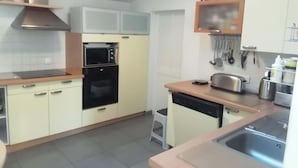 Une cuisine compacte équipée d’un four à micro-ondes, d’un four, d’un grille-pain et d’un lave-vaisselle.