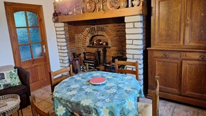 Un coin repas agrémenté d’une cheminée en briques, de meubles en bois et d’une nappe à motifs floraux.