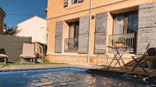 A swimming pool with a wooden deck, a chair, and a small table. - Gîte Lo Bornat: full of nature and sun, between sea and mountains (Puissalicon)