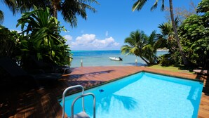 A pool with a view of the ocean, surrounded by palm trees and lounge chairs. - Villa Maharepa Beach by ENJOY VILLAS/3 bdrm with AC/2 bath/private pool + beach (Moorea-Maiao)
