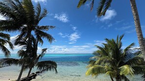 A beach with clear turquoise water, palm trees, and a white bench. - Villa Maharepa Beach by ENJOY VILLAS/3 bdrm with AC/2 bath/private pool + beach (Moorea-Maiao)
