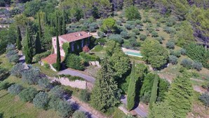 Un vaste domaine avec un bâtiment principal entouré d’une végétation luxuriante et doté d’une piscine.