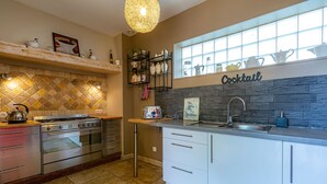 Een moderne keuken met een ingebouwde oven, een aanrecht met een koffieapparaat en een spatwand met een ruitpatroon.