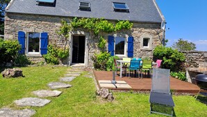 A stone house with a sloped roof, a wooden deck, and a stone pathway leading to the entrance. - BRETONNE LONGERE BETWEEN SEA AND COUNTRYSIDE (Plouhinec)