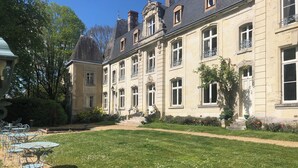A large, historic building with a well-maintained garden and outdoor seating area. - Château de la Voûte, facing south (Troo)