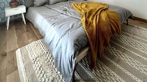 Een slaapkamer met een bed, twee nachtkastjes, een behangetje en een plafondlamp.