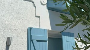 Een gebouw met witte muren, een blauwe deur en een raam met tegels.