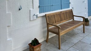Een houten bankje voor een gebouw met witte muren en blauwe luiken.
