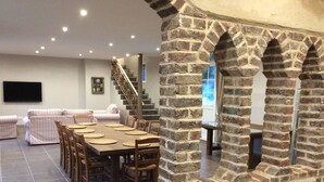 A dining area with a brick archway, a staircase, and a living room with a sofa and TV.