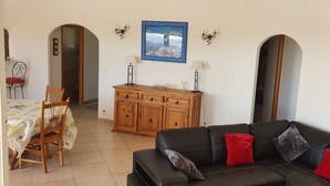 A living room with a black leather sofa, wooden cabinet, dining table with chairs, and a wall-mounted picture. - Very nice villa with heated pool (private pool in August and September)  (Lecci)