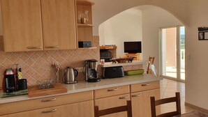 A kitchen with wooden cabinets, a coffee maker, and a television on a stand. - Very nice villa with heated pool (private pool in August and September)  (Lecci)