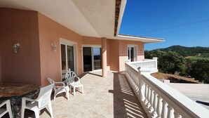 A balcony with a table and chairs, a view of the countryside, and a building with a pink facade. - Very nice villa with heated pool (private pool in August and September)  (Lecci)