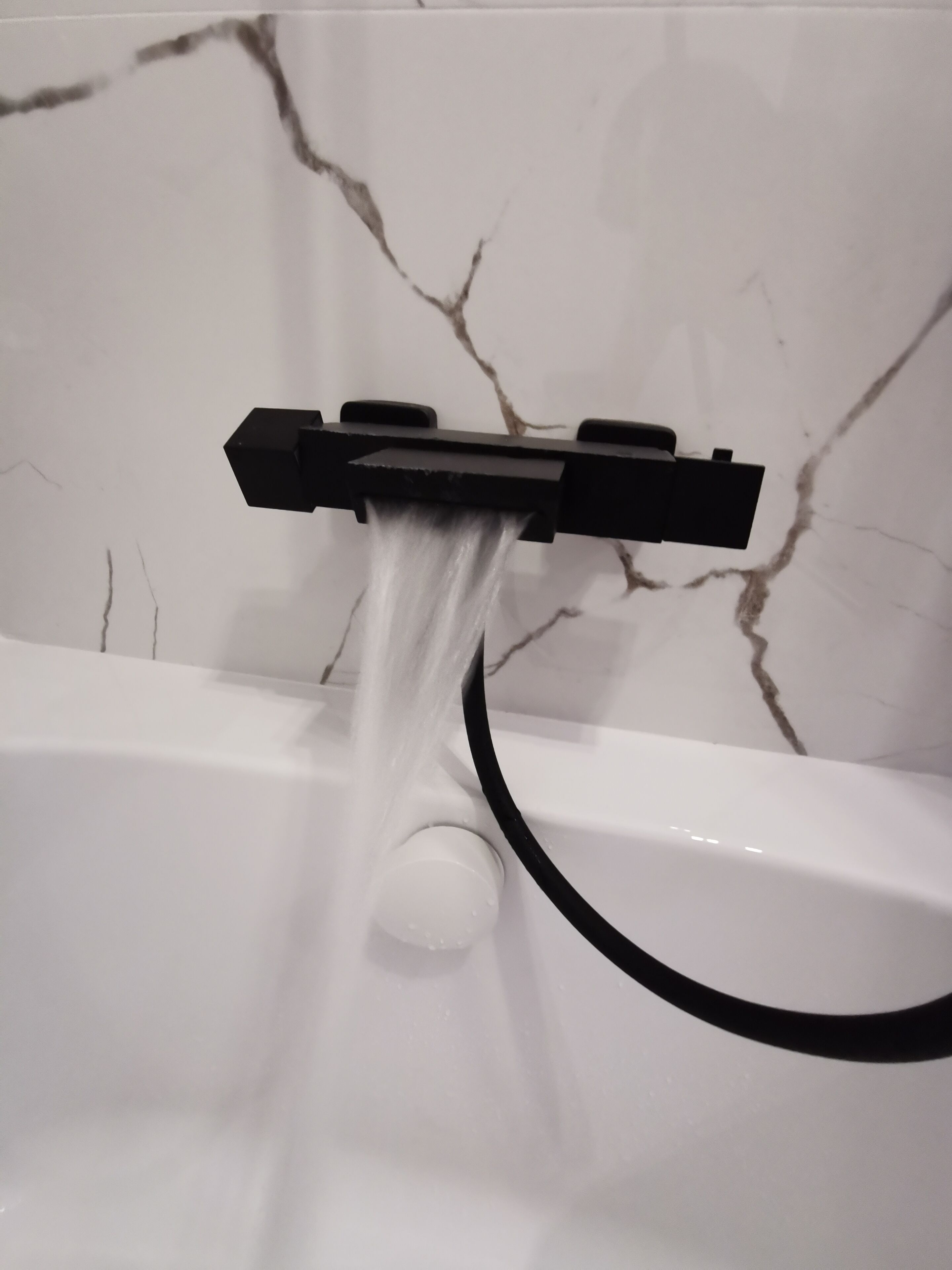 Ein Badezimmer mit einem weißen Marmorwaschbecken und einem schwarzen Wasserhahn.