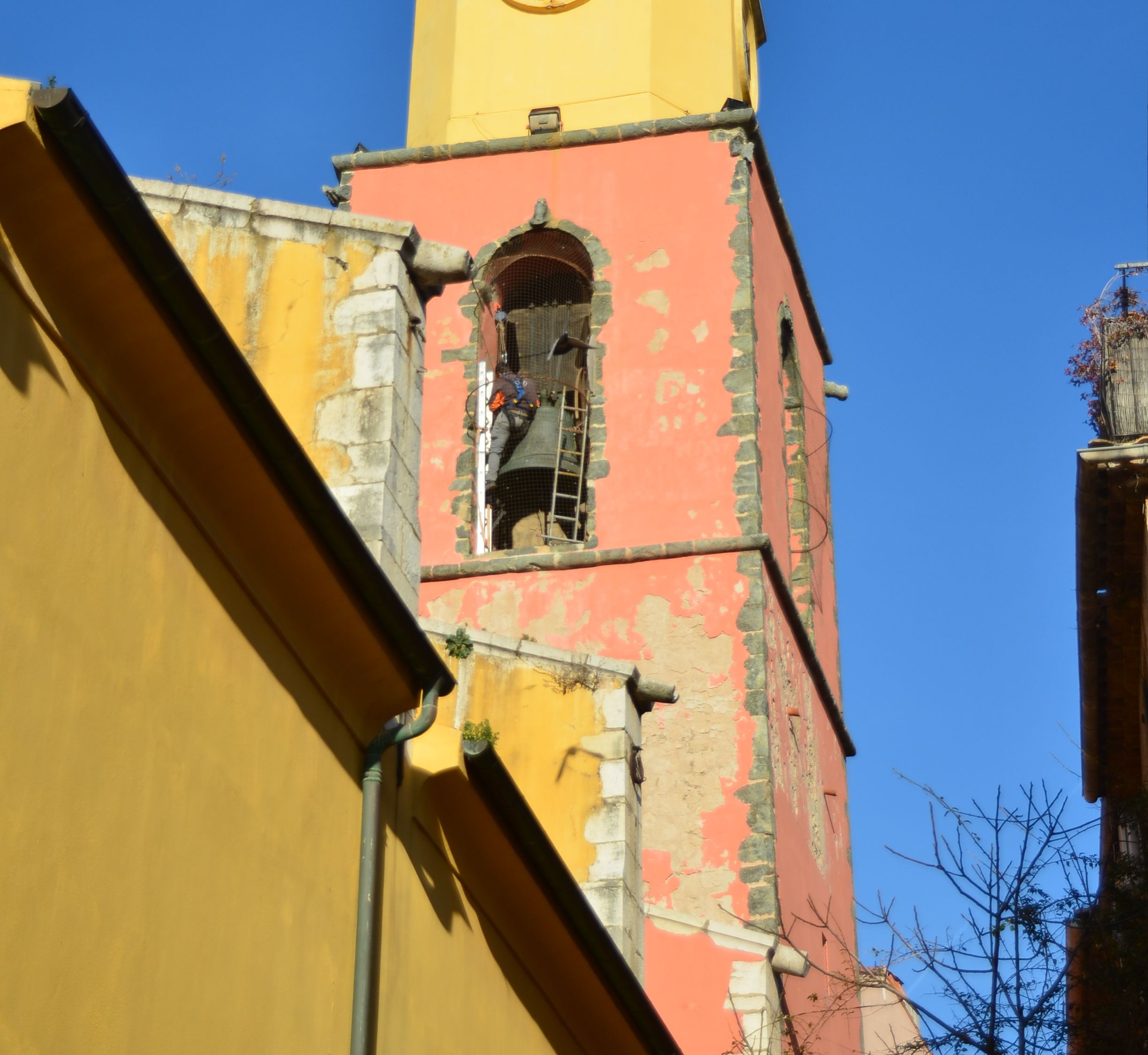 A yellow building with a clock tower, partially damaged facade, and visible pipes.